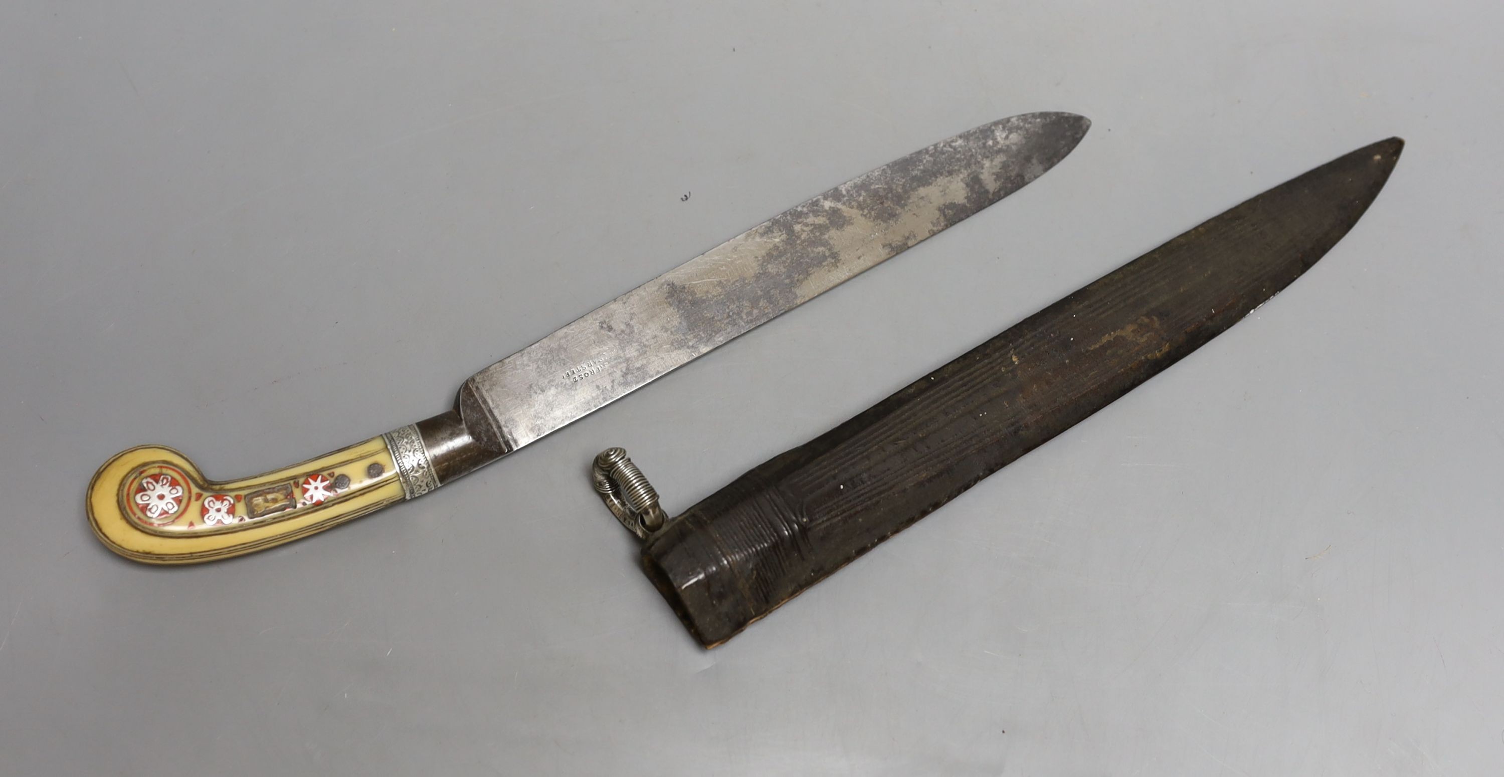 An African Arab knife, 19th century, carved ivory handle with silver inlays, leather covered wood sheath with silver ring, signed European blade 23cms.